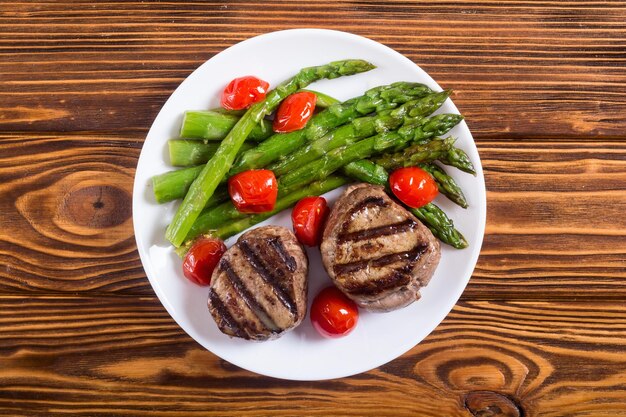 Grilled filet mignon with asparagus and tomatoes Beef sreak on rustic background