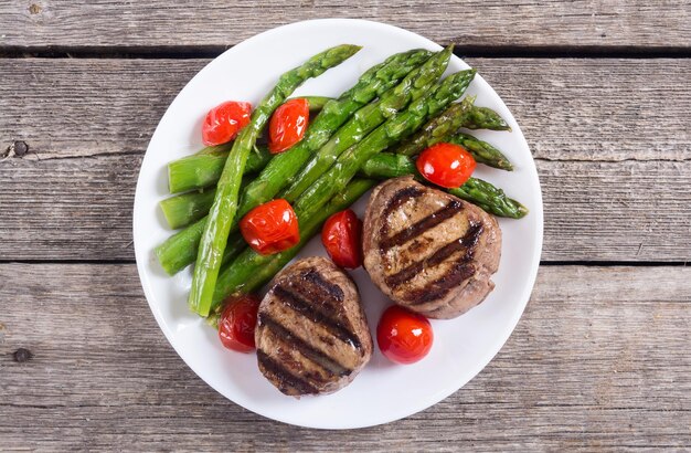Grilled filet mignon with asparagus and tomatoes Beef sreak on rustic background