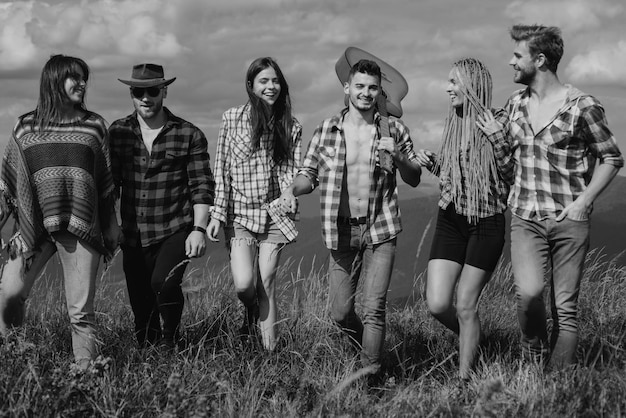 Group of friends hikers walking in mountains young men and women on camping countryside hiking group