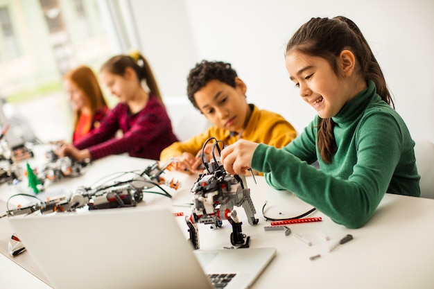Group of happy kids programming electric toys and robots at robotics classroom