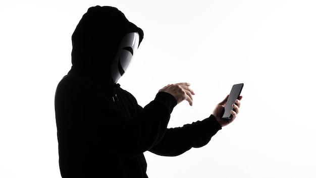 Hacker Anonymous and face mask with smartphone in hand