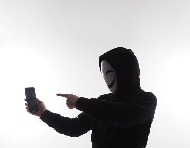 Hacker Anonymous and face mask with smartphone in hand