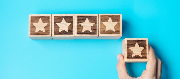 hand holding star block on blue background customer choose rating for user reviews service rating ranking customer review satisfaction evaluation and feedback concept