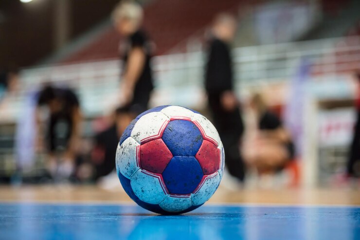 Foto handball ball on court' s floor blurred referees coaches and athletes and field background