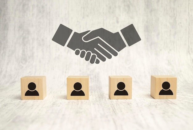 handshake icon screen on wooden cube block over employees wooden background