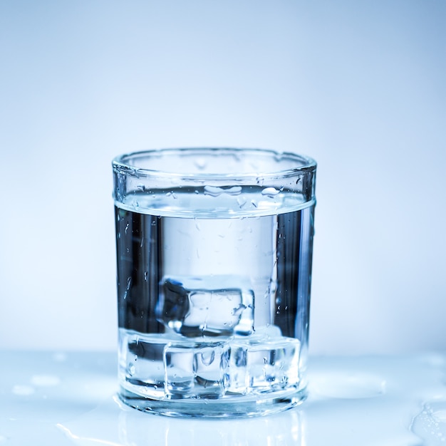 ice cube in glass of water isolated on white surface