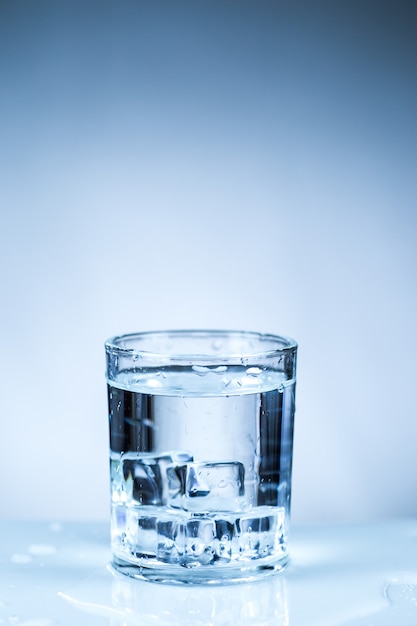 ice cube in glass of water isolated on white surface