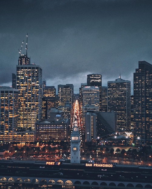 Illuminated buildings against cloudy sky at dusk