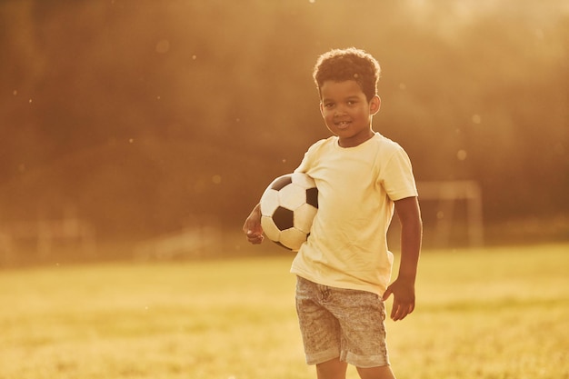 Illuminated by sunlight African american kid have fun in the field at summer daytime