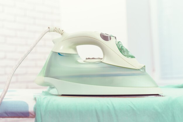 Iron on ironing board on light home interior 