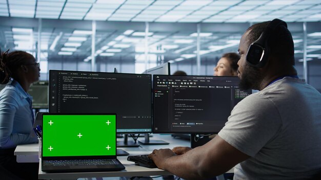 Isolated screen laptop next to programmer coding in server farm