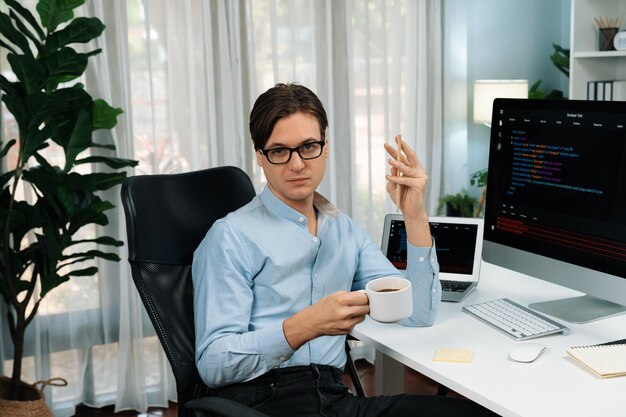IT developer looking camera holding coffee cup with coding on pc Pecuniary
