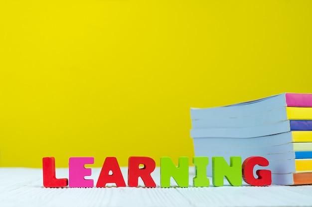 LEARNING text alphabet and pile of book with yellow background.