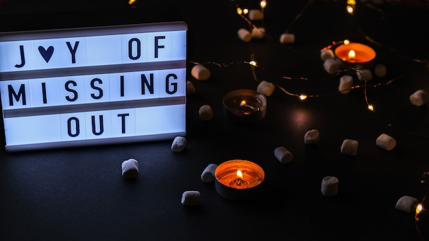 lightbox with text jomo joy of missing out. the concept of relaxation from information and gadgets. tea light candles. digital detox