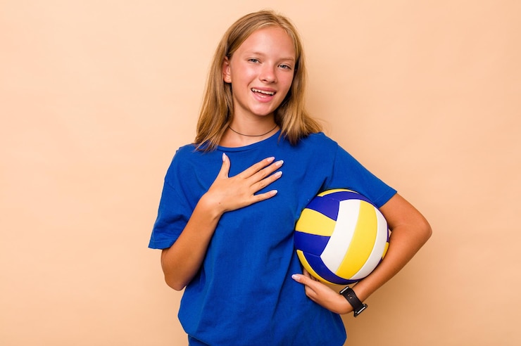 Foto little caucasian girl playing volleyball isolated on beige background laughs