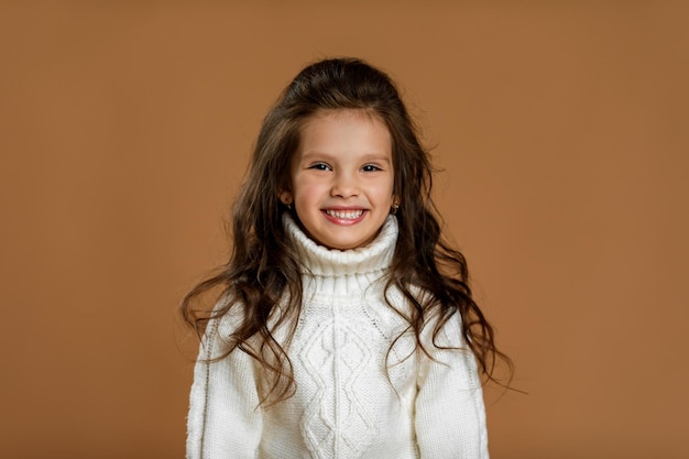 Little girl in white sweater looking to camera