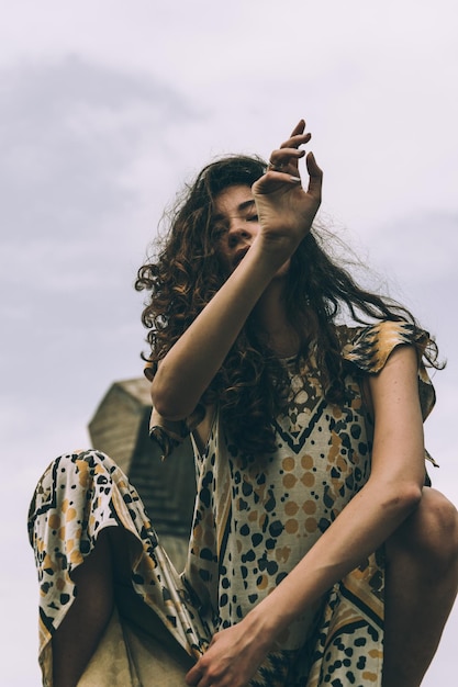 low angle portrait of woman crouching against sky