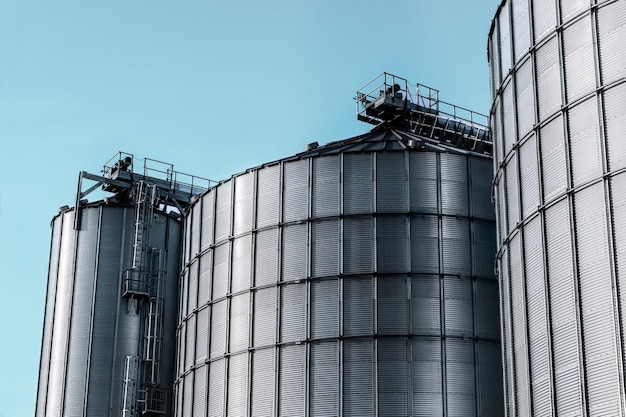 Low angle view of silos against clear blue sky