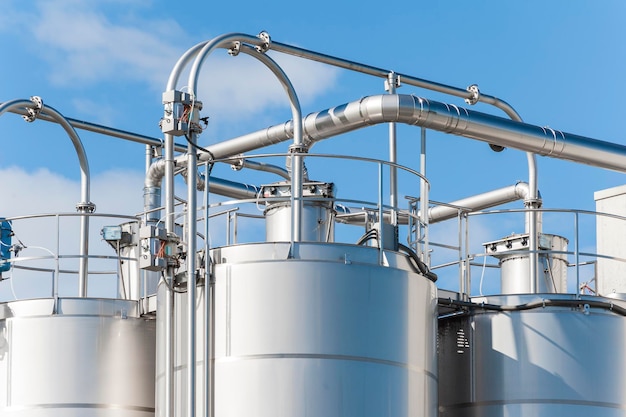 Low angle view of storage tanks against sky during sunny day