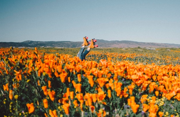 Low section of person wearing roller skating by blooming flowers