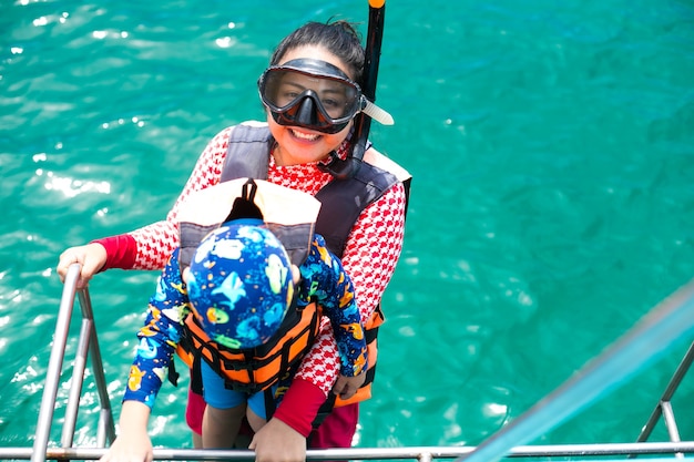 Lykkelig snorklende mor og sønn som har det gøy i havvannet og snorkler på karibisk ferie i Thailand