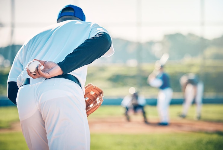 Foto man baseball and pitcher ready to throw ball for game match or victory shot on grass field at pitch male sports player with hand behind back with mitt in preparation for sport pitching outdoors