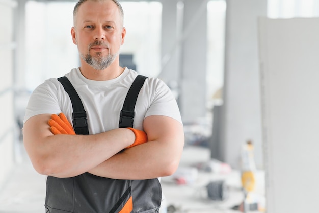 Man Builder Architect is standing in building Portrait of thinking builder Builder architect in unfinished building Architect in working uniform