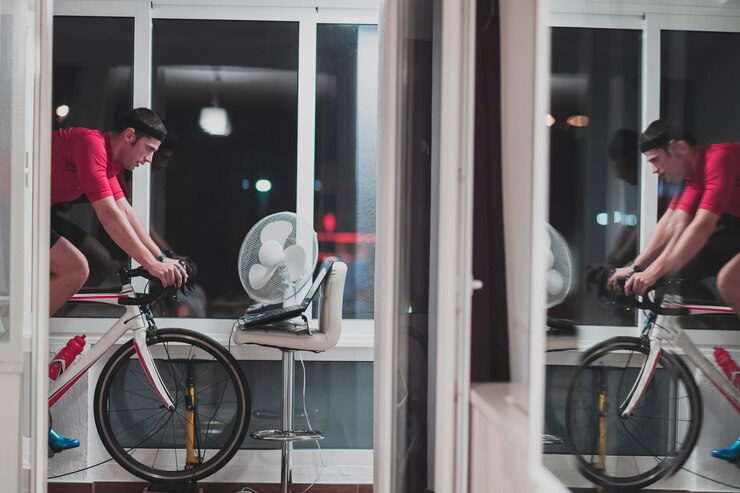 Foto man cycling on the machine trainer he is exercising in the home at night playing online bike racing game