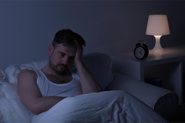 Man in bed with a clock on the table