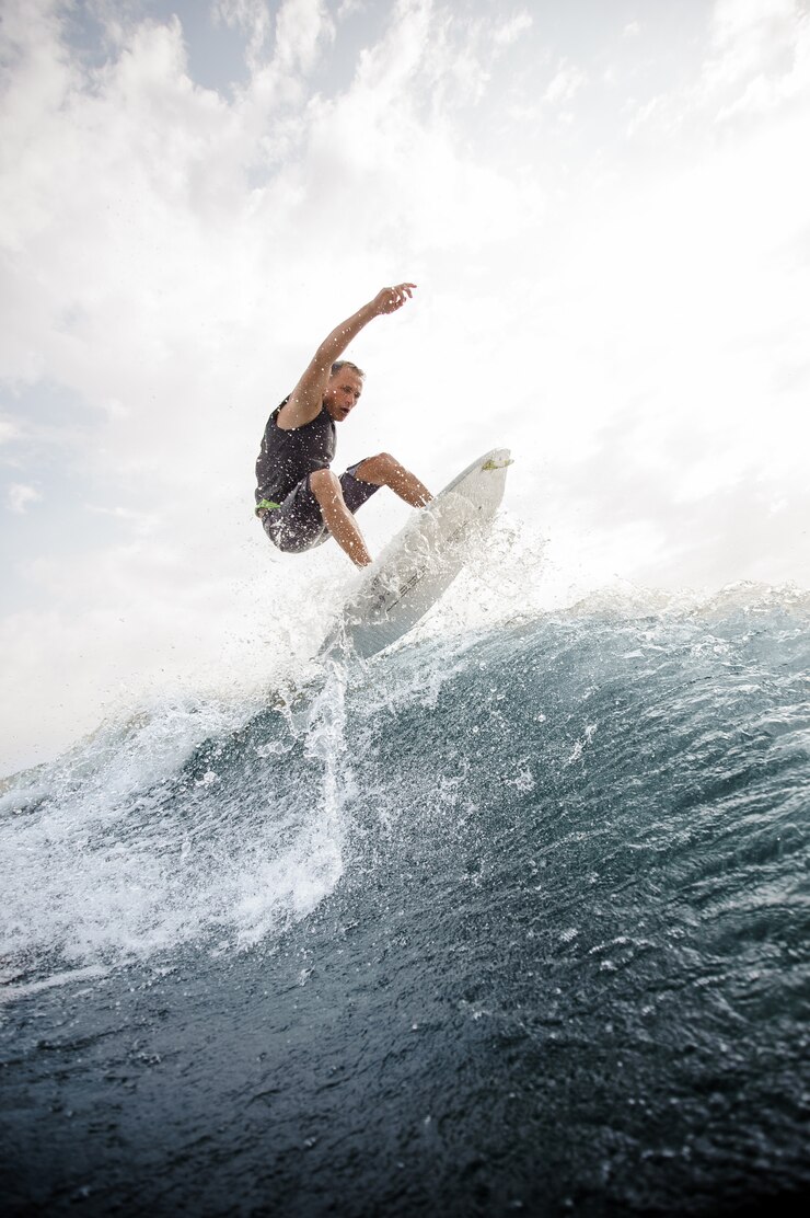 Foto man jumping on the white wakeboard down the blue water against grey sky