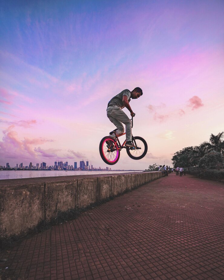 Foto man performing stunt on bicycle against sky during sunset