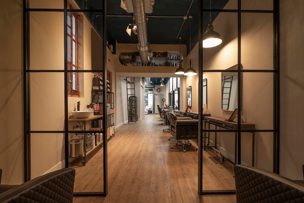 Metal and glass partition in a beauty salon with several armchairs lined up in front of mirrors hanging on the wall