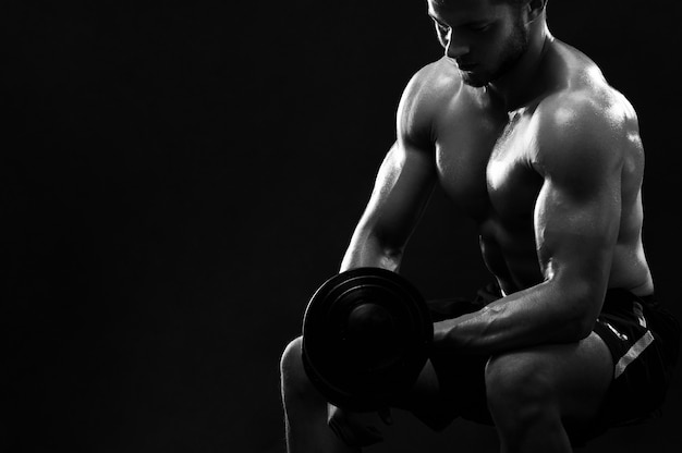 Monochrome shot of an athletic ripped young sportsman with dumbb