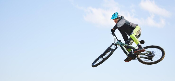 Foto mountain bike man and jump in blue sky for competition freedom or adventure on mockup space banner of athlete sports and bicycle in air for action cardio race and courage of stunt speed or risk