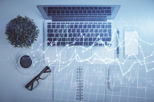 Multieksponering av valutadiagramtegning over bordbakgrunn med datamaskin Konsept for finansielle undersøkelser og analyser Toppvisning
