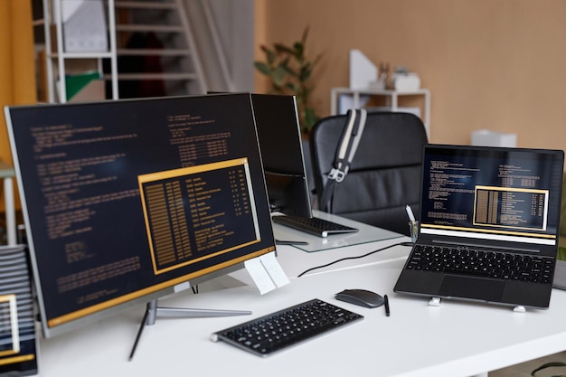 multiple computer devices with code lines on screen in it development office