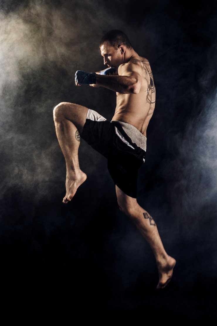Foto muscular kickbox or muay thai fighter punching in jump. smoke