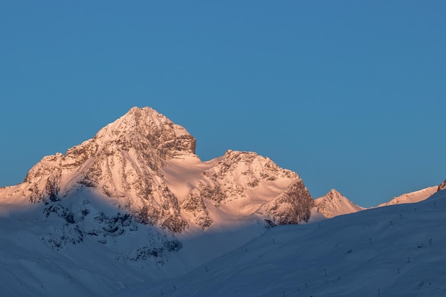Naturskjønn utsikt over snødekte fjell mot klar blå himmel
