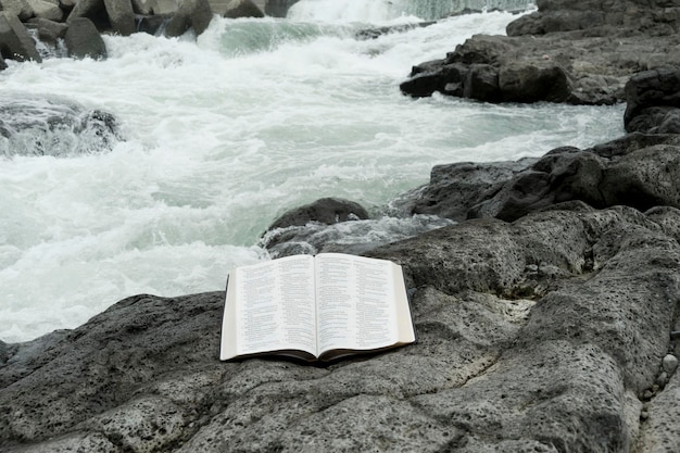 Open Holy Bible opened in Psalms 106 and 107 outdoors beside a river stream