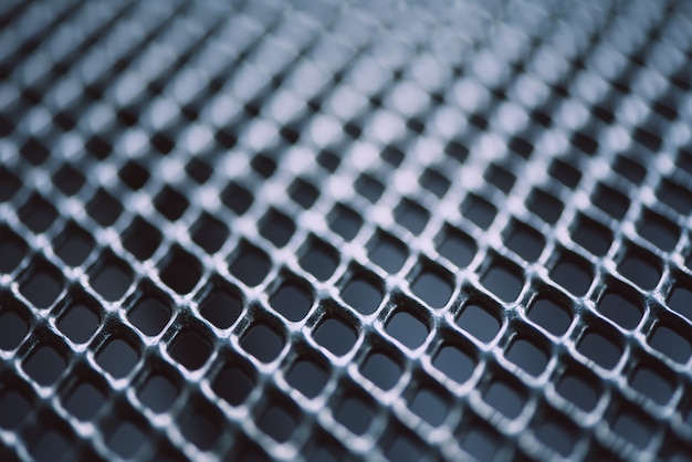 Overflate av gitterformet metallgjerde. Lett uskarp bakgrunn i rustfritt stål og aluminium. Makrotekstur