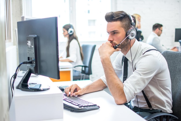 pensive business man with headset at workplace in office in front of the computer