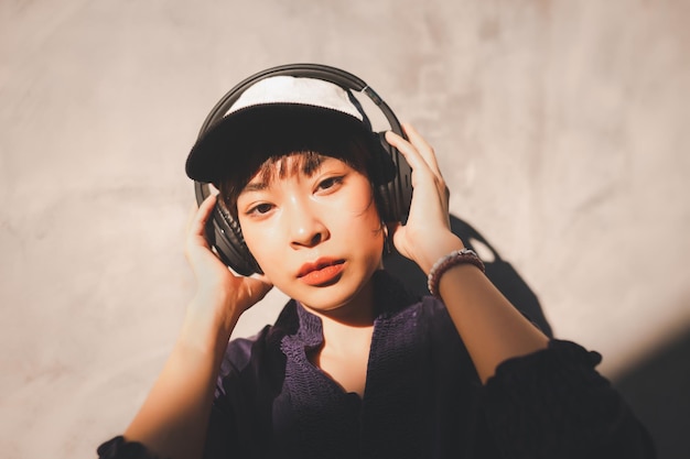 Portrait of girl wearing headphones against wall