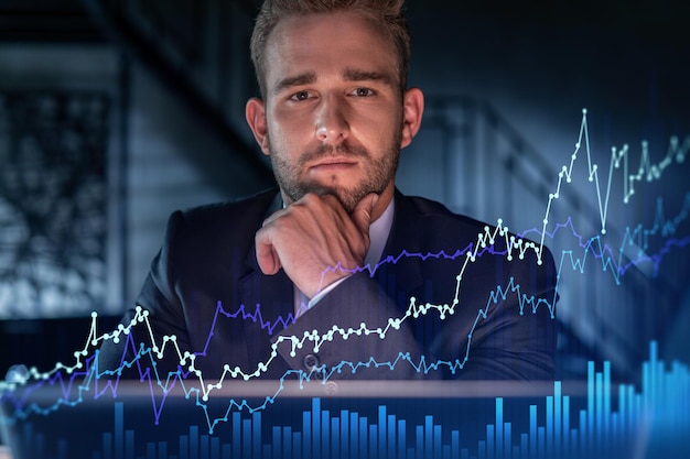 Portrait of handsome businessman in formal suit thinking how to optimize trading strategy at corporate finance fund Forex chart hologram over modern office background Hand on chin
