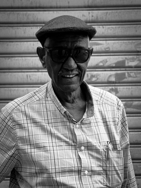 Portrait of old man wearing hat against wall