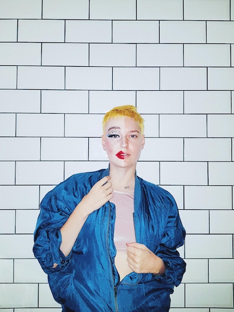 portrait of woman with painted face standing against wall