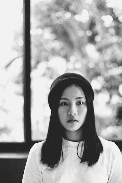portrait of young woman wearing cap against wall