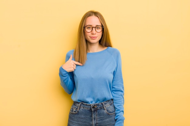 pretty caucasian woman looking proud confident and happy smiling and pointing to self or making number one sign