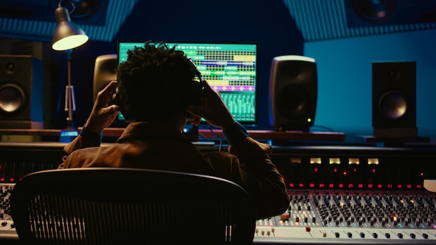 Professional tracking engineer using headphones to edit recorded tracks