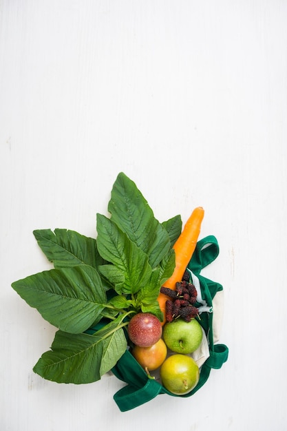 Raw vegetables and fruits with textile bag on white wooden table top view