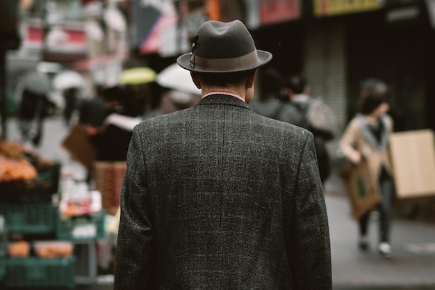 rear view of man wearing hat and coat while standing on street